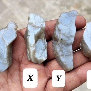 May include: Four rough, pale blue-grey stones labeled W, X, Y, and Z. Each stone features an irregular, jagged shape with a translucent, waxy texture and visible surface fractures. The stones are arranged in a row, displaying variations in size and form.