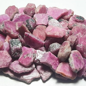 Peut inclure: Un tas de pierres précieuses brutes de rubis roses. Les pierres brutes sont de tailles et de formes variées.