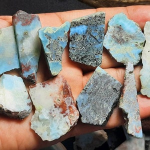 May include: A collection of blue, green, and white gemstone chips with a rough, irregular shape. The chips have a variety of patterns and textures.