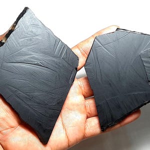 以下が含まれることがあります： 縞模様の入った、不規則な形の黒い黒曜石の塊が2つ。塊には「A」と「B」のラベルが貼られています。