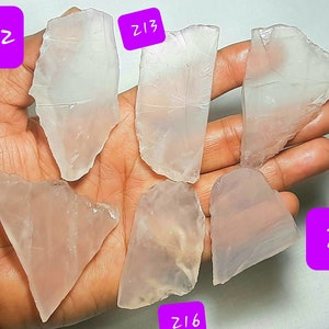 May include: Six pieces of clear, translucent, pink-hued, natural quartz crystal. The crystals are irregularly shaped and have a smooth, polished surface. The crystals are labeled with numbers Z12, Z13, Z14, Z15, Z16, and Z17.