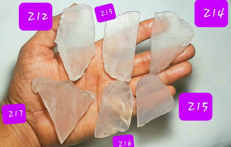 May include: Six pieces of clear, translucent, pink-hued, natural quartz crystal. The crystals are irregularly shaped and have a smooth, polished surface. The crystals are labeled with numbers Z12, Z13, Z14, Z15, Z16, and Z17.