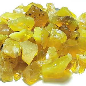 Puede incluir: Un montón de piedras preciosas de ópalo en bruto de color amarillo y naranja. Los ópalos son de varios tamaños y formas.