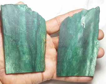 May include: Two pieces of green jade stone, one with a darker green color and the other with a lighter green color. The stones are smooth and have a natural, polished finish.