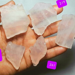 May include: Six pieces of clear, translucent, pink rose quartz crystals. The crystals are various shapes and sizes. The crystals are labeled with numbers: Z18, Z19, Z20, Z21, Z22, and Z22.
