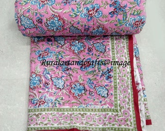 Op de afbeelding: Roze katoenen deken met een bloemenprint. De deken is opgerold en heeft een rode rand. De tekst "Ruralartandcrafts@image" is zichtbaar op de deken.