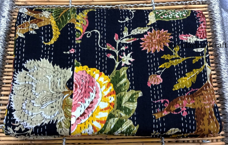 May include: Black kantha quilt with a floral pattern in shades of pink, yellow, green, and brown. The quilt is hand-stitched with white thread and has a traditional Indian design.