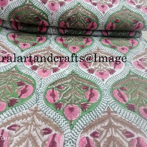 Pu&ograve; includere: Tessuto di cotone bianco con un motivo ripetitivo di fiori rosa e marroni e foglie verdi. Il tessuto &egrave; piegato a met&agrave; e il testo "Ruralartandcrafts@Image" &egrave; visibile.