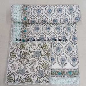 May include: A white cotton quilt with a floral pattern in shades of blue, green, and gray. The quilt is folded in half and has a border with a repeating pattern.