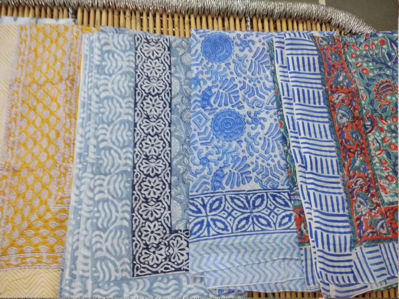 May include: Five different fabric swatches with various blue and white patterns. The swatches are arranged horizontally and are all made of a soft, lightweight fabric.