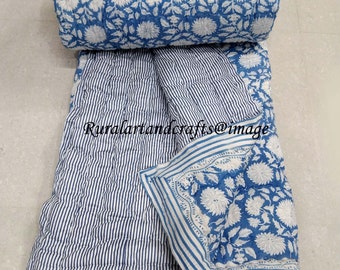Könnte beinhalten: Eine blaue und weiße Baumwolldecke mit Blumenmuster. Die Decke ist in der Hälfte gefaltet und die Blumen Seite zeigt nach oben. Die andere Seite der Decke hat weiße Streifen auf blauem Hintergrund.