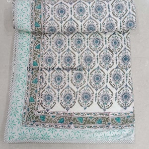 May include: White cotton quilt with a blue and green floral pattern. The quilt has a border with a light blue and white star pattern.