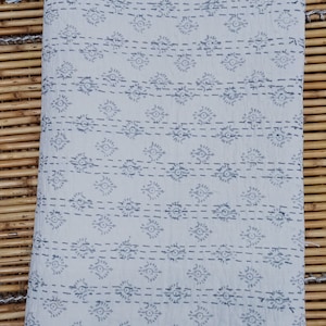 May include: A white cotton kantha quilt with a grey and white geometric pattern. The quilt is hand-stitched and has a fringed edge.