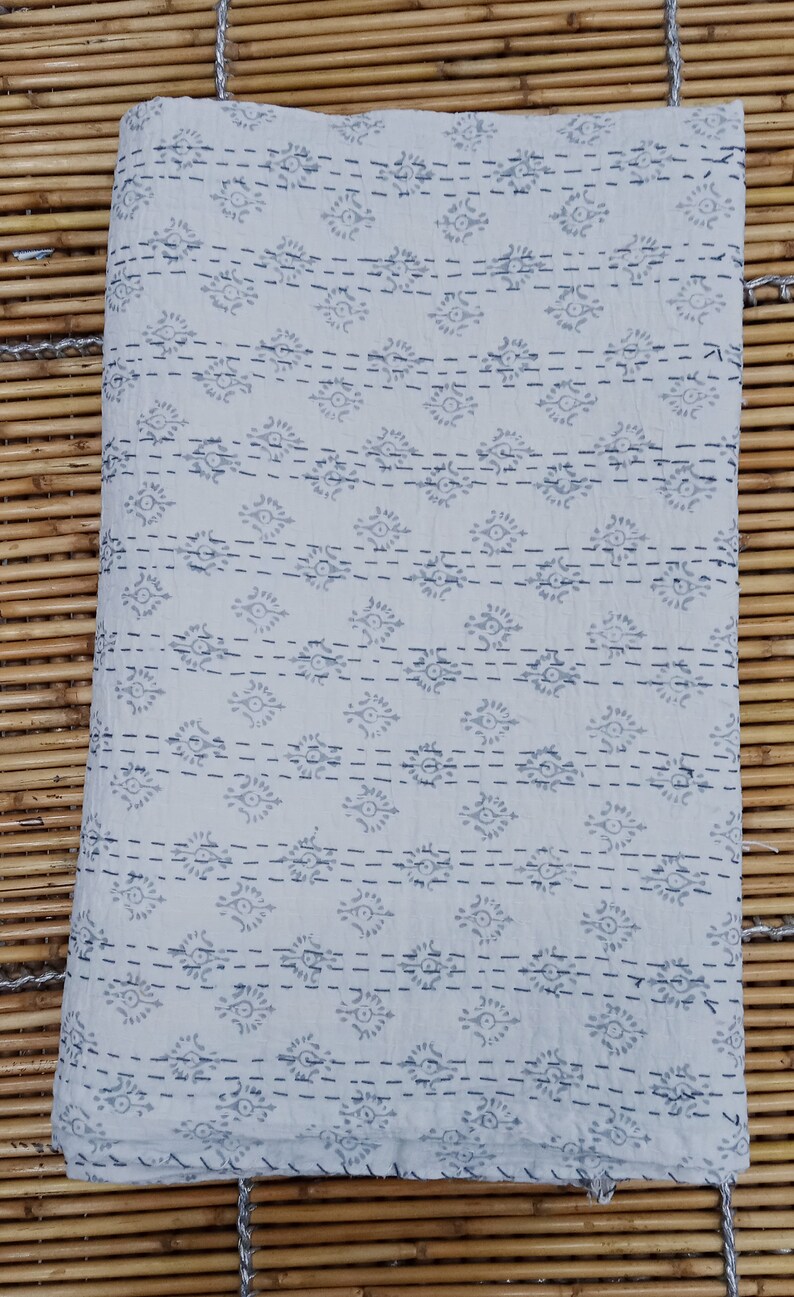 May include: A white cotton kantha quilt with a grey and white geometric pattern. The quilt is hand-stitched and has a fringed edge.
