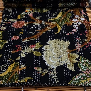 May include: Black kantha quilt with a floral pattern featuring white, green, and brown flowers. The quilt is hand-stitched with white thread and has a traditional Indian design.