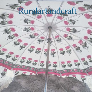 Op de afbeelding: Een witte paraplu met een roze en groene bloemenprint. De paraplu is open en de binnenkant van de kap is zichtbaar. De tekst "Ruralartandcraft" is op de paraplu gedrukt.