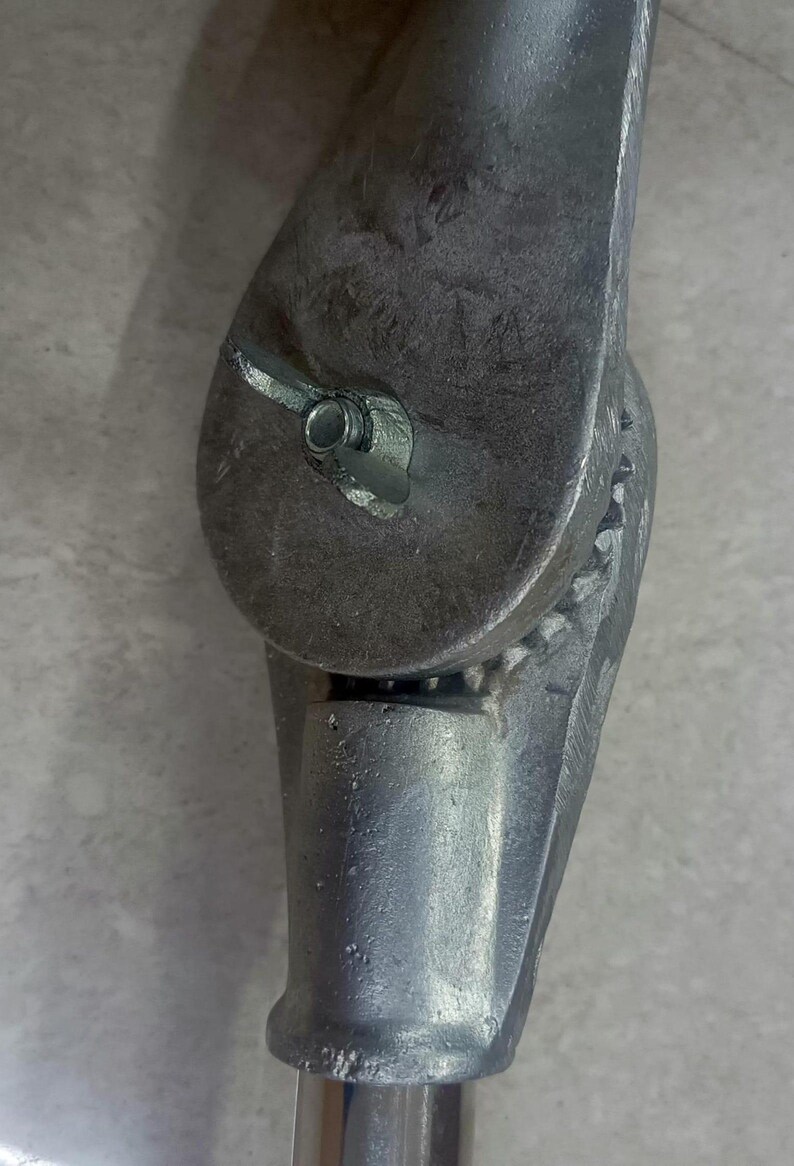 Op de afbeelding: Een verstelbare ondersteuning van zilverkleurig metaal met een draaiknop en een tandwielmechanisme. De ondersteuning is ontworpen om aan een paal of andere constructie te worden bevestigd.