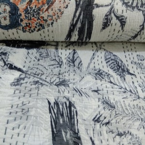 May include: A white kantha quilt with a black and gray floral pattern. The quilt is hand-stitched and has a soft, textured surface.
