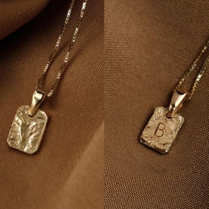 Puede incluir: Dos collares de oro con colgantes rectangulares. Un colgante es liso y el otro tiene la letra "B" grabada.