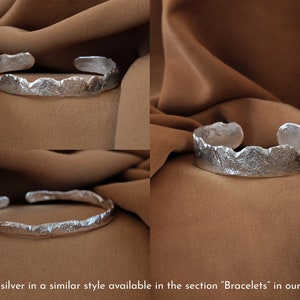 May include: A silver bracelet with a textured, organic design. The bracelet is open and has a slightly curved shape.