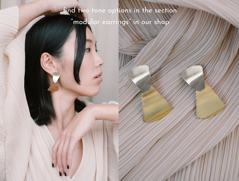 May include: Two-tone geometric earrings with a gold and silver finish. The earrings are made of two pieces, a larger triangle shape and a smaller curved shape. The earrings are shown on a model wearing a white shirt.
