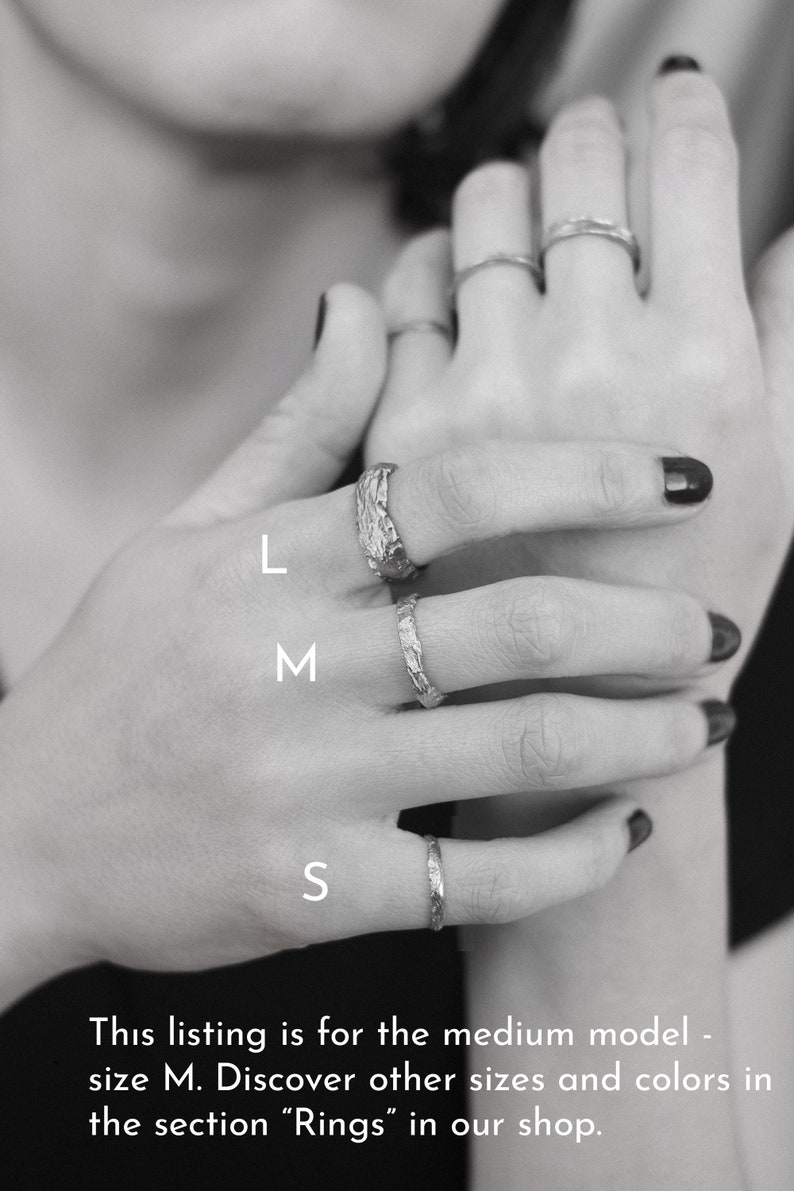 May include: A set of three silver rings, labeled L, M, and S, on a hand. The rings are textured and have a hammered finish.