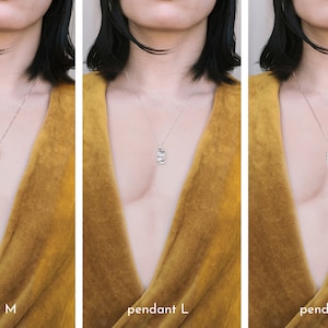 May include: Three silver necklaces with different sized pendants. The pendants are rectangular and have a textured surface. The necklaces are shown on a person wearing a mustard yellow top.