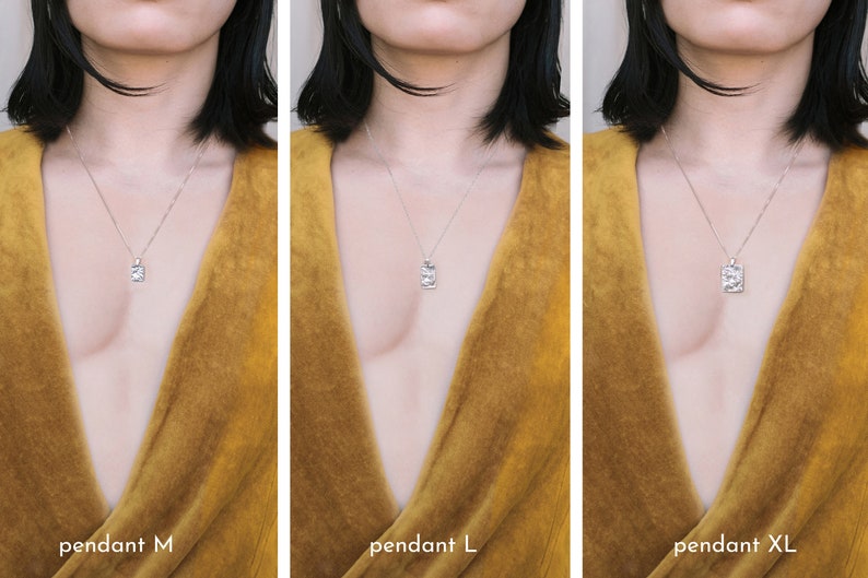 May include: Three silver necklaces with different sized pendants. The pendants are rectangular and have a textured surface. The necklaces are shown on a person wearing a mustard yellow top.