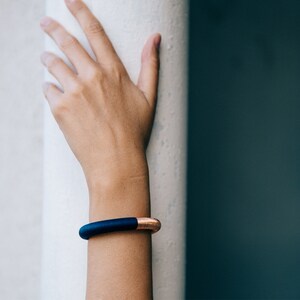 Pu&ograve; includere: Un braccialetto blu e rame con un design minimalista. Il braccialetto &egrave; realizzato in un materiale morbido e flessibile e ha un aspetto elegante e moderno.