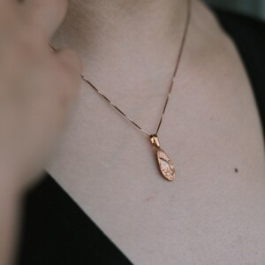 Peut inclure: Un collier d&eacute;licat en cha&icirc;ne dor&eacute;e avec un pendentif en forme de larme textur&eacute;.