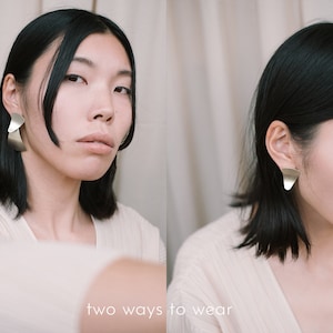 May include: Two ways to wear a silver geometric earring. The earring is shown worn in two different ways, one with the earring hanging down and the other with the earring worn closer to the ear.