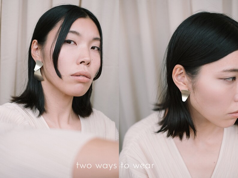 May include: Two ways to wear a silver geometric earring. The earring is shown worn in two different ways, one with the earring hanging down and the other with the earring worn closer to the ear.