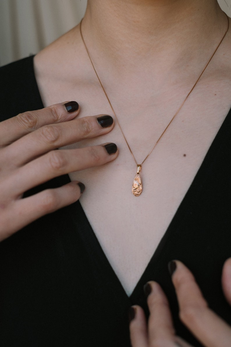 Peut inclure: Un collier en cha&icirc;ne dor&eacute;e avec un pendentif en forme de larme textur&eacute;.