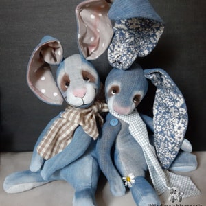 May include: Two denim blue bunny plushies with white polka dot ears and floral patterned ears. One bunny is wearing a brown and white checkered scarf and the other is wearing a white and blue checkered scarf. The bunnies are sitting on a gray surface. The text "ilfilo di mais.blogspot.it" is on the bottom right corner of the image.