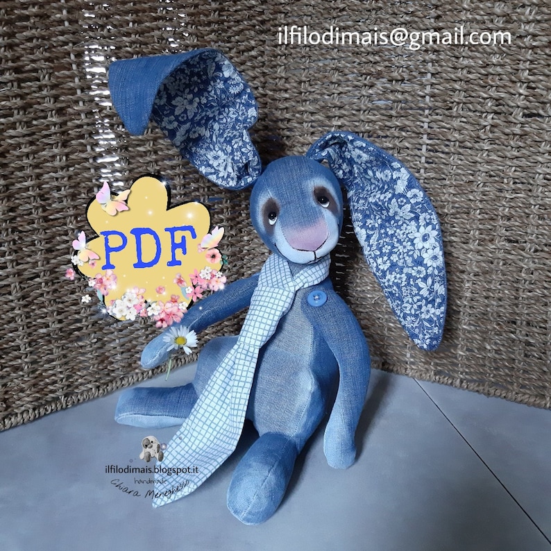 May include: A blue denim bunny rabbit with a white and blue checkered scarf. The bunny is holding a white daisy. The bunny is sitting on a light gray surface. A yellow flower with the word "PDF" in blue letters is in the background.