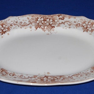 May include: A white oval serving platter with a brown floral design around the edge.