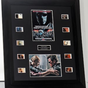 Könnte beinhalten: Ein schwarzer gerahmter Display mit einem Terminator 3: Rise of the Machines Filmplakat, einem Foto von Arnold Schwarzenegger und Claire Danes und acht Filmzellenrahmen. Der Text "Terminator 3 Screen Run Movie Frames Limited Edition" ist unter dem Plakat gedruckt.