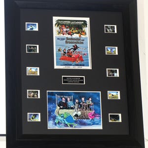 May include: A black framed display featuring a Bedknobs and Broomsticks movie poster, a scene still of the cast on a bed, and ten individual film cells. A central plaque reads Movie Favourites Screen Run Movie Frames Limited Edition.