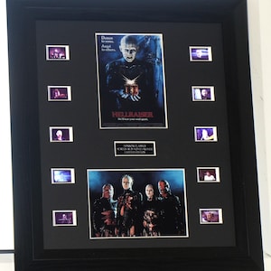 May include: A black framed display featuring a Hellraiser movie poster, a group scene photograph, and ten individual film cells. The poster includes the text Demon to some, Angel to others and Hellraiser. A plaque reads Horror Classics Screen Run Movie Frames Limited Edition.