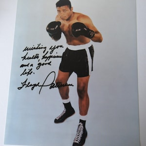 May include: A vintage photograph of a boxer in black shorts, black boxing gloves, and black shoes. The image includes handwritten text that reads "wishing you health, happiness and a good life. Floyd Patterson."