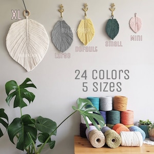 Può includere: Cinque dimensioni di arazzi da parete a forma di piuma in macramè, in bianco, grigio, giallo, verde e rosa. Il testo "XL", "Large", "Default", "Small" e "Mini" è visualizzato sotto ogni arazzo. Il testo "24 Colori 5 Dimensioni" è visualizzato sotto gli arazzi.