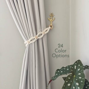 May include: White macrame curtain tieback with wooden beads, attached to a gold anchor hook. The text "24 Color Options" is visible in the image.