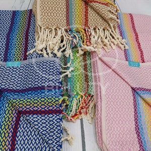 May include: Four colorful striped towels with diamond patterns and fringe. The towels are in shades of blue, pink, brown, and green.