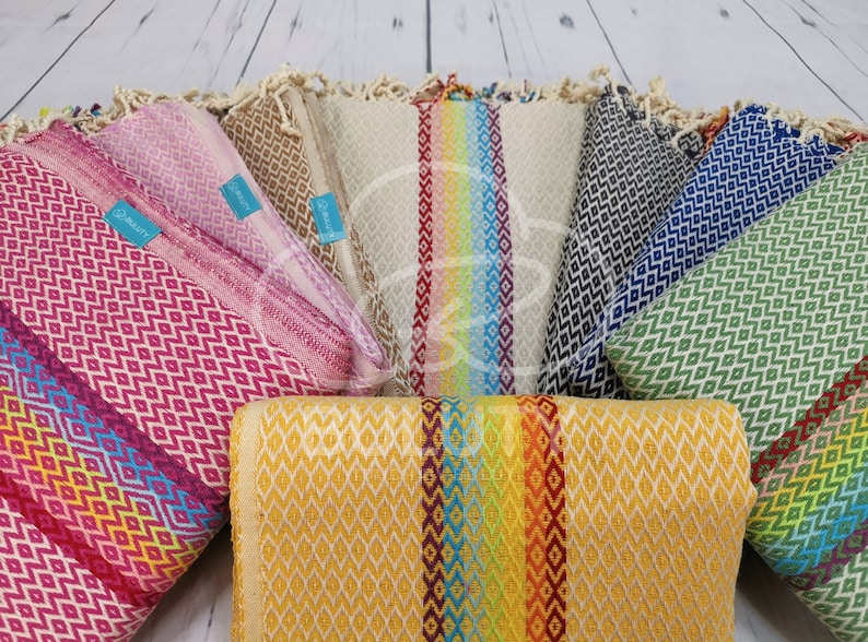 May include: A collection of colorful Turkish towels with geometric patterns. The towels are arranged in a circle with the ends of the towels overlapping. The towels are made of cotton and have a soft, absorbent texture.