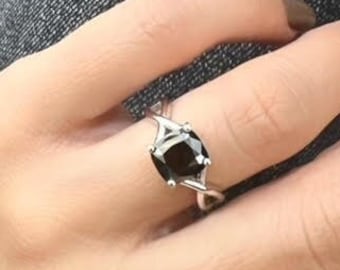 May include: A silver ring with a black square-shaped gemstone. The ring has a twisted band design.