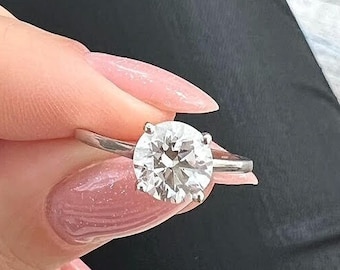 May include: A close-up of a silver ring with a large, round, clear diamond.