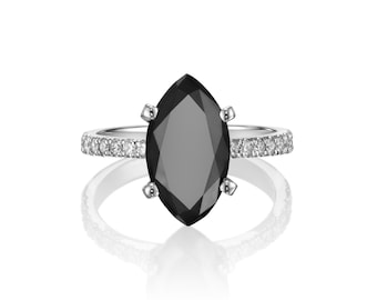 May include: A marquise-shaped black diamond engagement ring with a white gold band and a row of small diamonds around the band.
