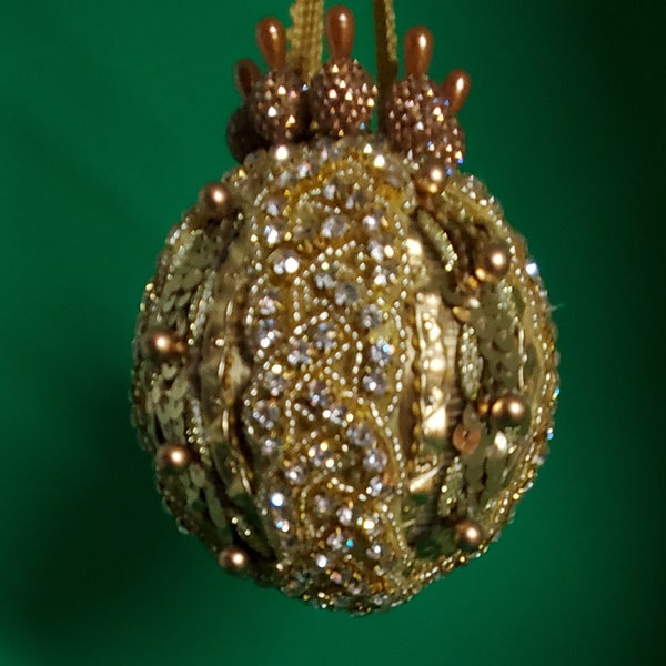 Des strass clairs et une tresse de perles dorées sur une bordure dorée et des paillettes avec des perles dorées décorent cette décoration de Noël faite à la main (boule de 7,6 cm).