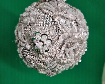 Broderad silverspets med pärlor och paljettdetaljer över en bas av silverfärgade strassstenar. Julgransprydnad (7,5 cm boll)