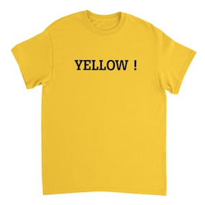 Pode incluir: Uma t-shirt de manga curta em amarelo brilhante com a palavra YELLOW ! impressa em letras maiúsculas pretas com serifa no centro do peito. A peça tem um decote redondo clássico e uma bainha com um corte direito padrão.